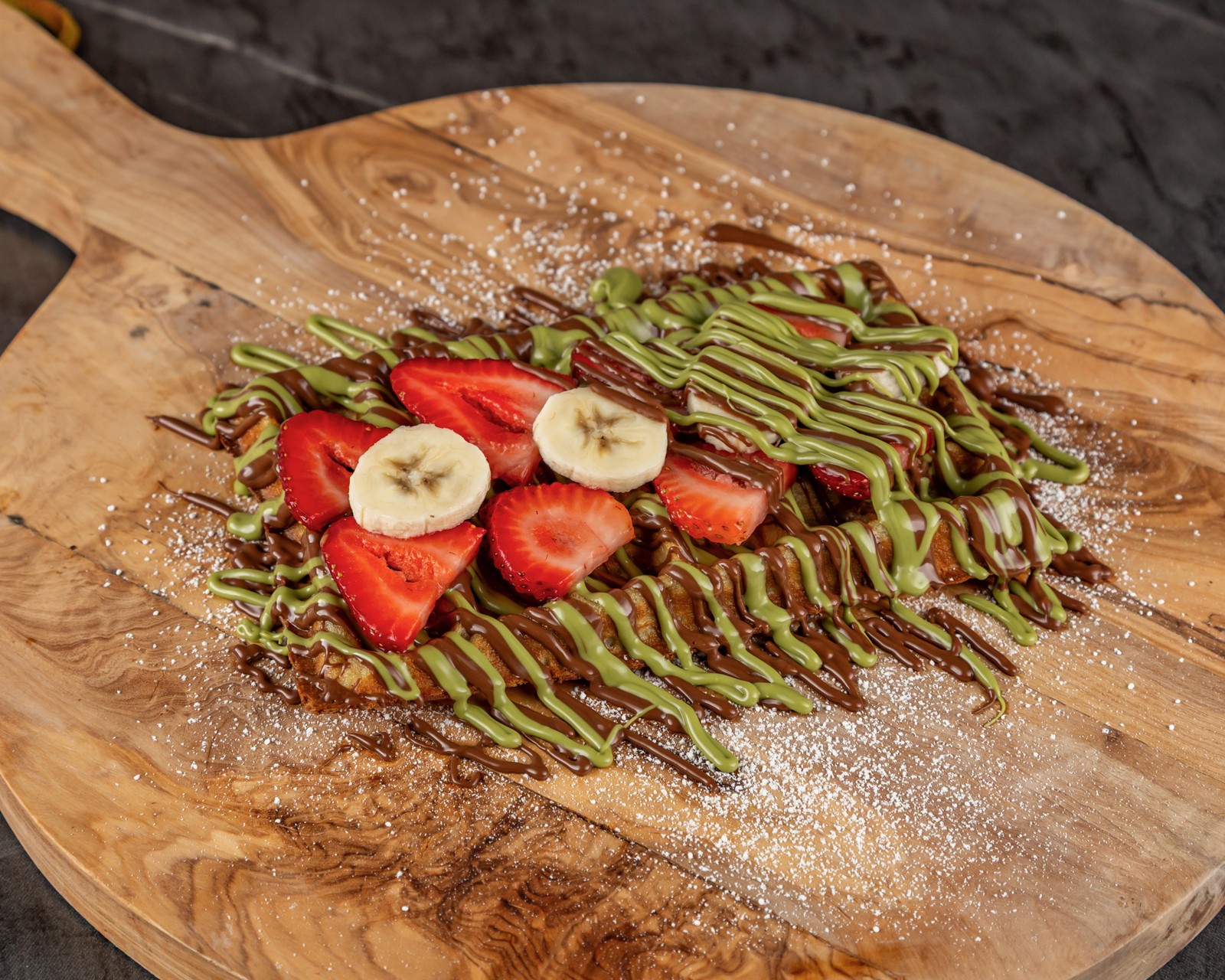 Our Belgian waffle with strawberries, banana slices, chocolate and pistachio drizzle