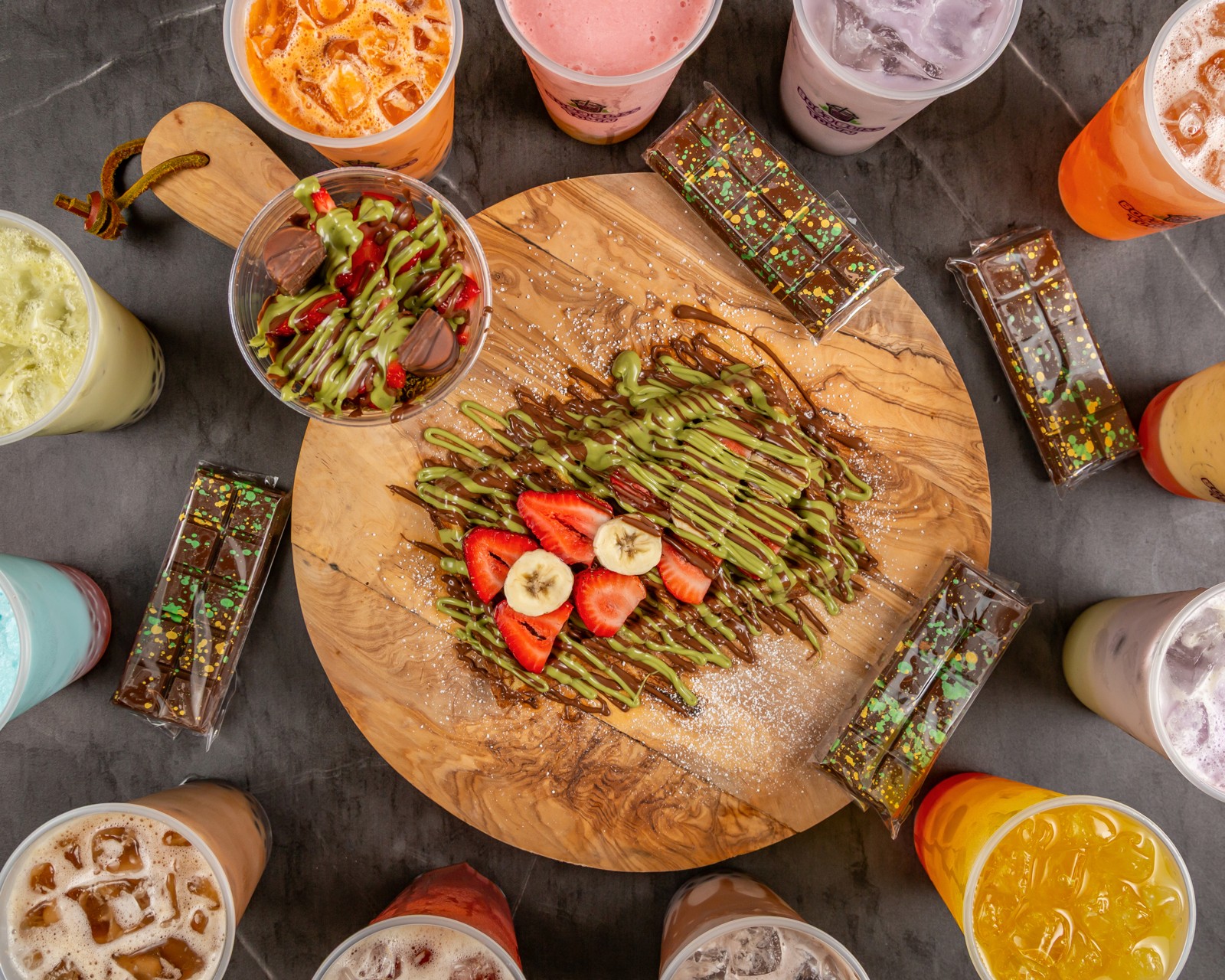 Overhead view of our waffle, Dubai Strawberry Cup, chocolate bars and colorful boba drinks